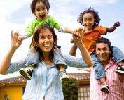 happy Mexican family with kids riding on parent's shoulders