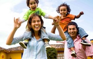 happy Mexican family with kids riding on parent's shoulders