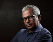 older immigrant man with glasses and serious expression
