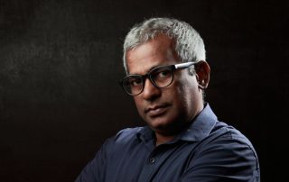 older immigrant man with glasses and serious expression
